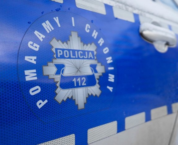 Policyjna gwiazda na drzwiach radiowozu i wokół niej napis: Pomagamy i chronimy